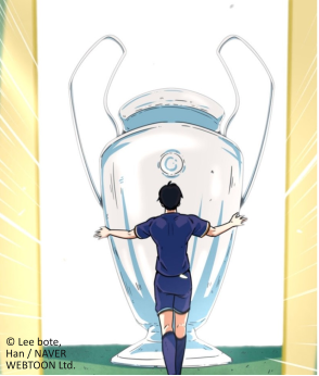 A soccer player stands in front of a giant trophy, arms outstretched, gazing in awe at the coveted Champions League cup.